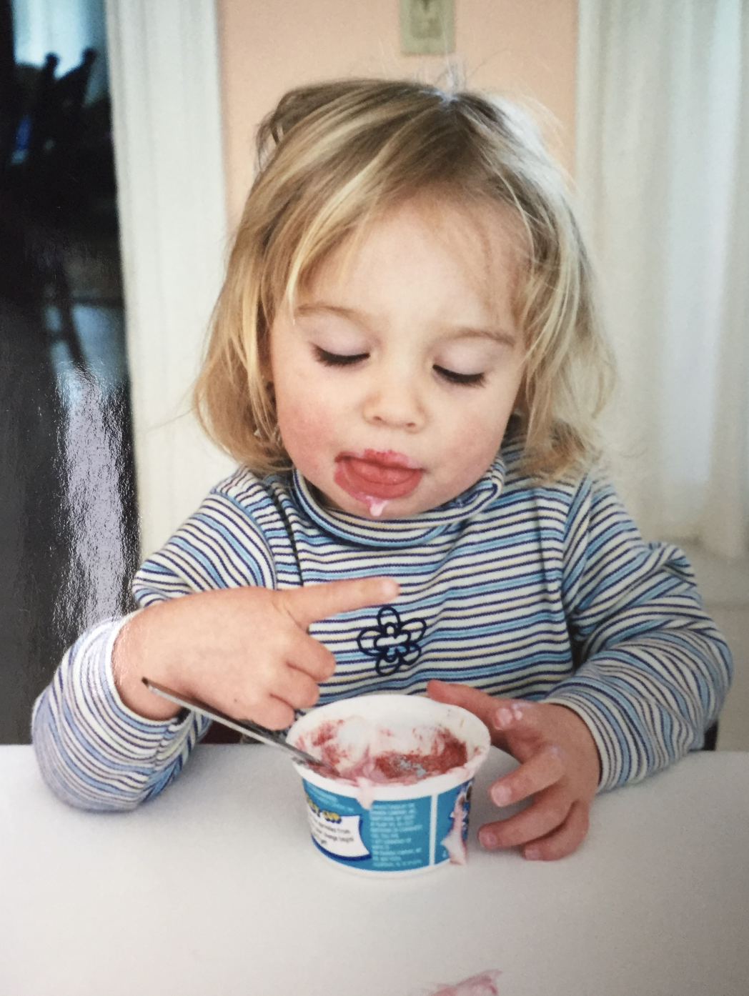 Little girl eating ice cream with her hands.